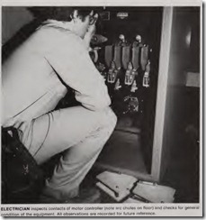 ELECTRICIAN inspects contacts of motor controller (note arc chutes on floor) and checks for general condition of the equipment. All observations are recorded for future reference.