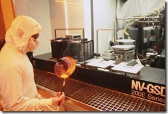 Figure 4.1. This silicon fab worker wears the puffy all-over bunny suit and gloves required in the clean room. He's holding a partially fi